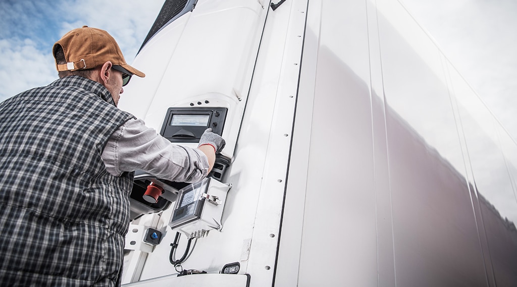 Truck driver adjusting temperature on refrigerated semitrailer.